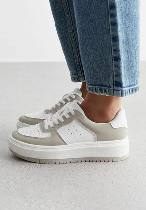 Zapatillas de deporte de baja caña con una puntera de cuero blanco, detalles en gamuza gris claro, diseño perforado y una gruesa suela de goma blanca.