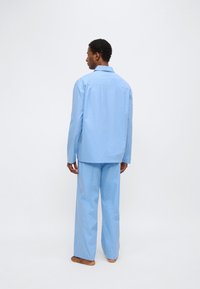 Σετ πιτζάμες με ανοιχτό μπλε ρίγες, που περιλαμβάνει πουκάμισο με κουμπιά και μακριά μανίκια και αντίστοιχο φαρδύ παντελόνι, με ομαλή υφή.