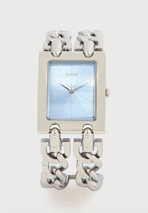 Montre-bracelet à maillons en argent avec un cadran rectangulaire bleu et des aiguilles argentées indiquant 10h10, marquée Guess sur le cadran.