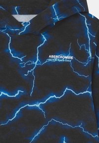 Felpa nera con un motivo di fulmini blu, caratterizzata da un logo bianco "Abercrombie Established 1892" sul petto e una consistenza morbida.