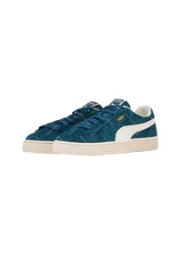 Sneaker in suede teal con dettagli bianchi sui lati e suola in gomma beige texturizzata. Presenta lacci blu e etichette sul linguetta con il marchio.