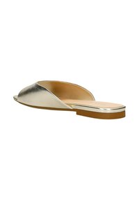 Sandale à glissière en métal doré avec bout ouvert, design de la tige courbé, semelle plate et texture en cuir lisse. Forme minimaliste et épurée.