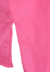 Jasnoróżowa bawełniana tkanina o gładkiej fakturze, z czystymi szwami i bocznym rozcięciem dla dodatkowych detali i wentylacji.