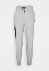 Graue Sweatpants aus weichem Material mit einem Kordelzugbund, schmal zulaufenden Beinen, seitlicher Reißverschlusstasche und Logo-Highlight auf der Vorderseite.