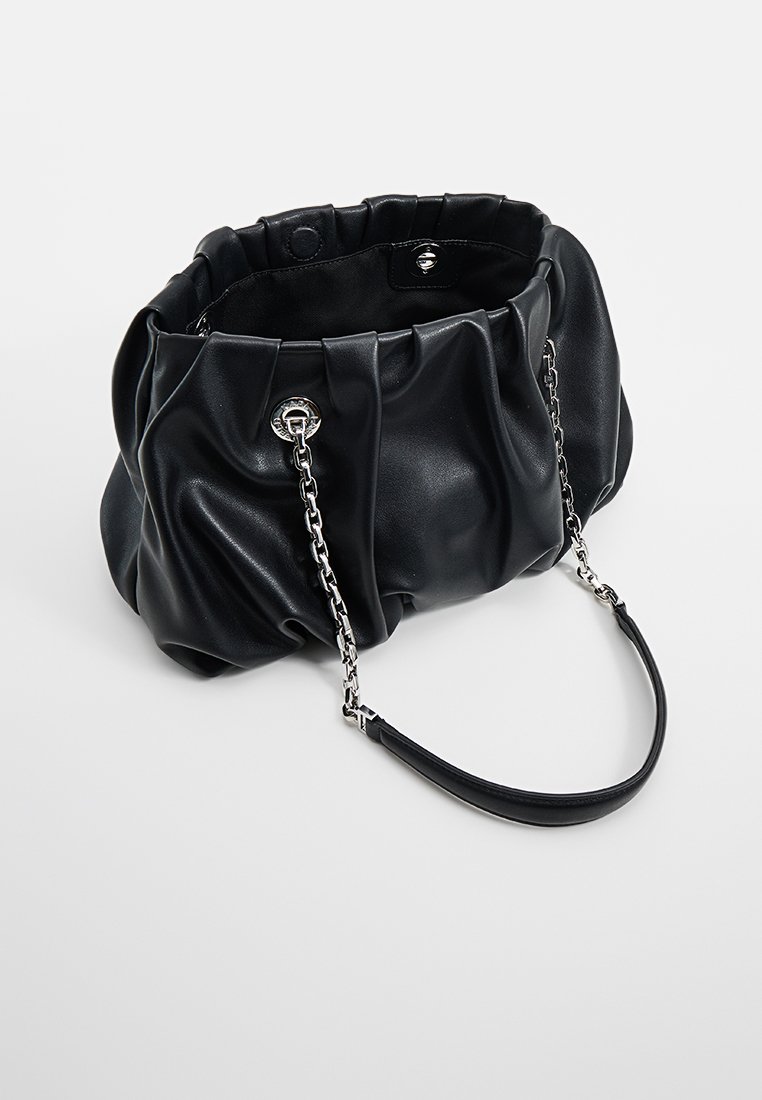 Bolso de mano de cuero sintético negro con pliegues, de forma estructurada, acento de cadena plateada y una textura suave. Cuenta con un asa corta y un cierre.