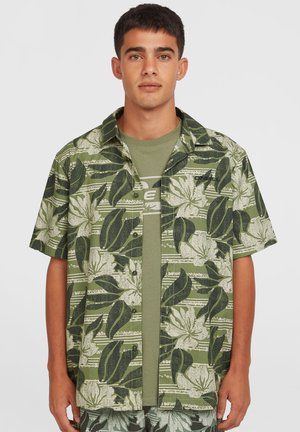 Kortærmet skjorte i grøn bomuld med et blomster- og bladmønster. Båret med en ensfarvet grøn t-shirt under. Casual design.