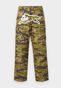 Παντελόνι cargo καμουφλάζ σε πράσινο, καφέ και μαύρο με πλαϊνές τσέπες και λευκό σχέδιο ενός ζώου που πηδά στο πίσω μέρος. Κατασκευασμένο από βαμβάκι.