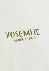 Hele roheline T-särk, millel on tumeoliivroheline tekst "YOSEMITE", allpool on väiksemas fondis kirjatükk "NATIONAL PARK". Valmistatud puuvillast.
