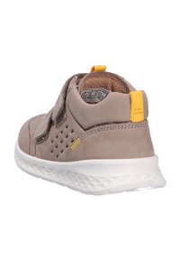 Baskets grises pour enfants avec semelle blanche, languette jaune au talon, côtés perforés et bandes Velcro, vues de dos.