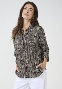 Black and white patterned blouse featuring a wave design, button-down front, and three-quarter sleeves. Soft fabric with a relaxed fit.