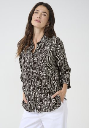 Zwart-wit geblokte blouse met een golfpatroon, knoopsluiting aan de voorkant en driekwart mouwen. Zachte stof met een ontspannen pasvorm.