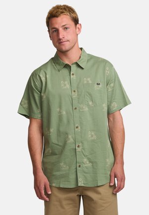 Camisa de botones de manga corta, verde claro, con un bolsillo, patrón de palmeras en beige y botones marrones.