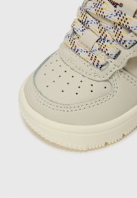 Jasnoszare sneakersy z teksturowaną skórzaną cholewką, perforowanym przodem i wielokolorowymi plecionymi sznurówkami. Gruba biała gumowa podeszwa.