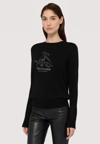 Svart stickad tröja med långa ärmar och rundad halsringning, prydd med en grå broderad grafisk design av hundar och texten "TRUSSARDI GENTLE SOCIETY."