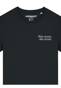 Zwarte katoen t-shirt met ronde hals; voorzien van witte tekst met de tekst "Was muss, das muss." Het label toont de merknaam "watapparel."