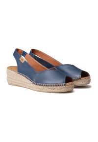 Navy leather open-toe slingback shoes with jute-wrapped wedge soles. Features a tan leather interior and decorative stitching along the edges.