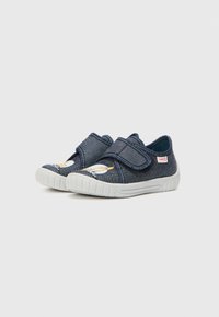 Mörkblå kanvas slip-on skor med vita gummisulor och kardborreband; har en broderad design på tån.