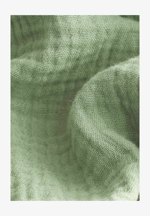 Hellgrüner, strukturiertes Gewebe mit einem gewebten Muster, das eine weiche Oberfläche und einen leichten Glanz zeigt, drapiert, um seine Falten und Oberflächen zu betonen.