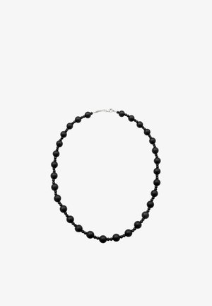 Collier de perles noires avec des perles rondes petites et grandes alternées, fixé par un fermoir mousqueton en argent, posé à plat en forme circulaire.