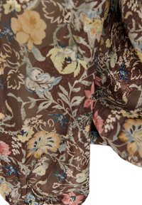Καφέ ύφασμα με floral σχέδιο που περιλαμβάνει κίτρινα, μπλε, ροζ και λευκά λουλούδια και πράσινα φύλλα σε ελαφρύ, διάφανο υλικό.