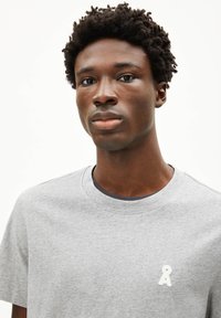 Grijze katoenen T-shirt met een ronde halslijn en een klein wit geborduurd logo op de borst. Korte mouwen en een zachte textuur.