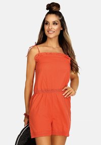 Czerwony romper z teksturowanej tkaniny, z falbanami przy dekolcie i koronkowym pasem w talii. Regulowane ramiączka, krótka długość.