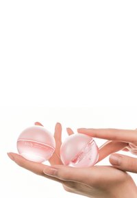 Deux pots ronds roses de soin de la peau étiquetés "Abib" tenus dans une main. Les pots ont une finition brillante et des parties inférieures transparentes, contenant un produit gélifié.