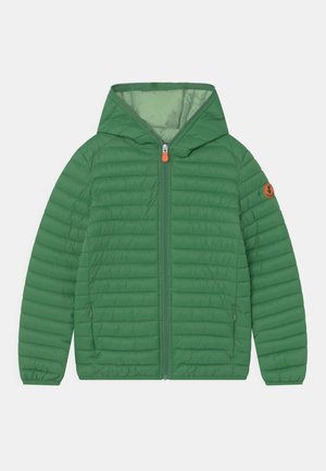 Veste matelassée légère verte avec capuche, fermeture éclair à l'avant, deux poches latérales zippées et un patch logo rond sur la manche gauche.