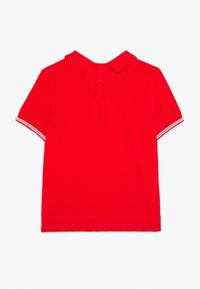 Czerwona koszulka polo z bawełny z klasycznym kołnierzykiem, dwoma guzikami i białymi paseczkami na rękawach. Gładkie plecy, standardowy krój.
