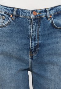 Μπλε τζιν παντελόνι με μέτριο πλύσιμο, με πορτοκαλί ραφές, κλείσιμο με χάλκινο κουμπί και μπροστινές τσέπες. Λείο υφή, κλασική εφαρμογή.