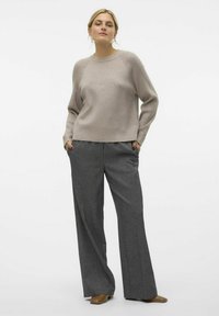 Beige Strickpullover mit Raglanärmeln, kombiniert mit grauen, hoch taillierten, weiten Hosen. Sanfte Textur, minimalistisches Design, subtile elegante Akzente.