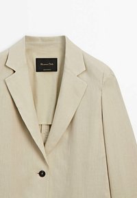 Blazer beige avec un col à revers cranté, une fermeture à un bouton et un tissu lisse et léger. L'étiquette indique "Massimo Dutti, Fabriqué au Portugal."