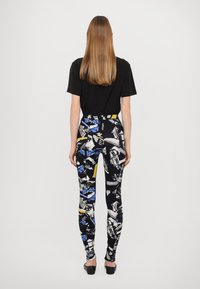 Svart t-shirt och mönstrade leggings med blå, vita och gula mönster på en svart bakgrund. Slät tyg med en åtsittande silhuett.