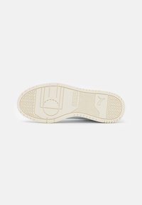 Hvid sneakersål med struktureret gummi for greb, og med PUMA-logo samt mønstrede traction-elementer for stabilitet.