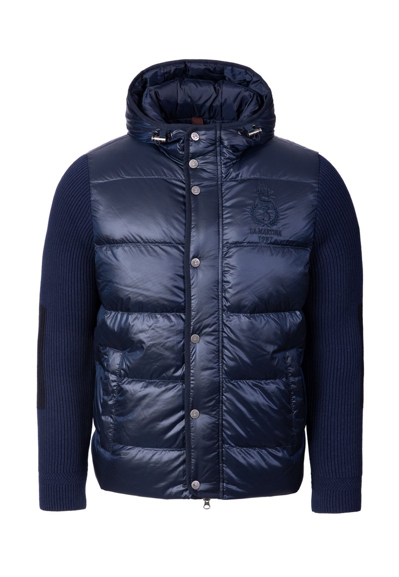 Giacca imbottita blu navy con cappuccio, parte anteriore trapuntata lucida, maniche in maglia a costine, tasche frontali e dettagli argentati.