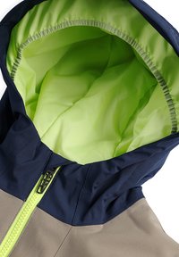 Veste imperméable avec un design bicolore, dotée d'une capuche bleue marine et d'un intérieur vert vif. Fermeture éclair et texture douce.