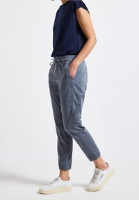 Marinen t-shirt med kort ärm i kombination med ljusgrå, smal tapered cargo-byxor med sidfickor och elastiska muddar, stylat med vita sneakers.