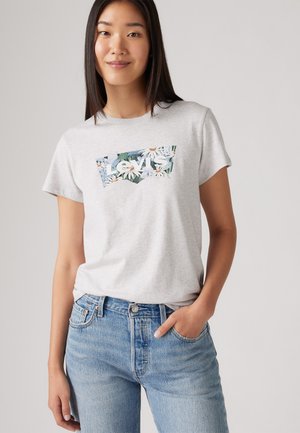 Graues T-Shirt mit kurzen Ärmeln und floralem Levi's Logo-Graphic, kombiniert mit hellblauen Jeans im klassischen Fünf-Taschen-Design.