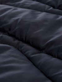 Tmavě modrá izolovaná tkanina s hladkým povrchem, obsahující prošívané části a jemné liniové vzory pro další detail.