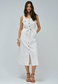 Witte denim midi-jurk met verstelbare banden, knopen aan de voorkant en een strik taille. Heeft verticale stiksels en een split aan de voorkant.