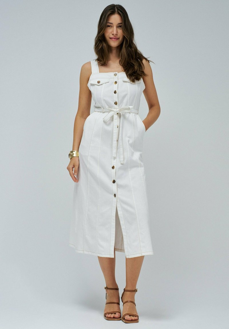 Witte denim midi-jurk met verstelbare banden, knopen aan de voorkant en een strik taille. Heeft verticale stiksels en een split aan de voorkant.