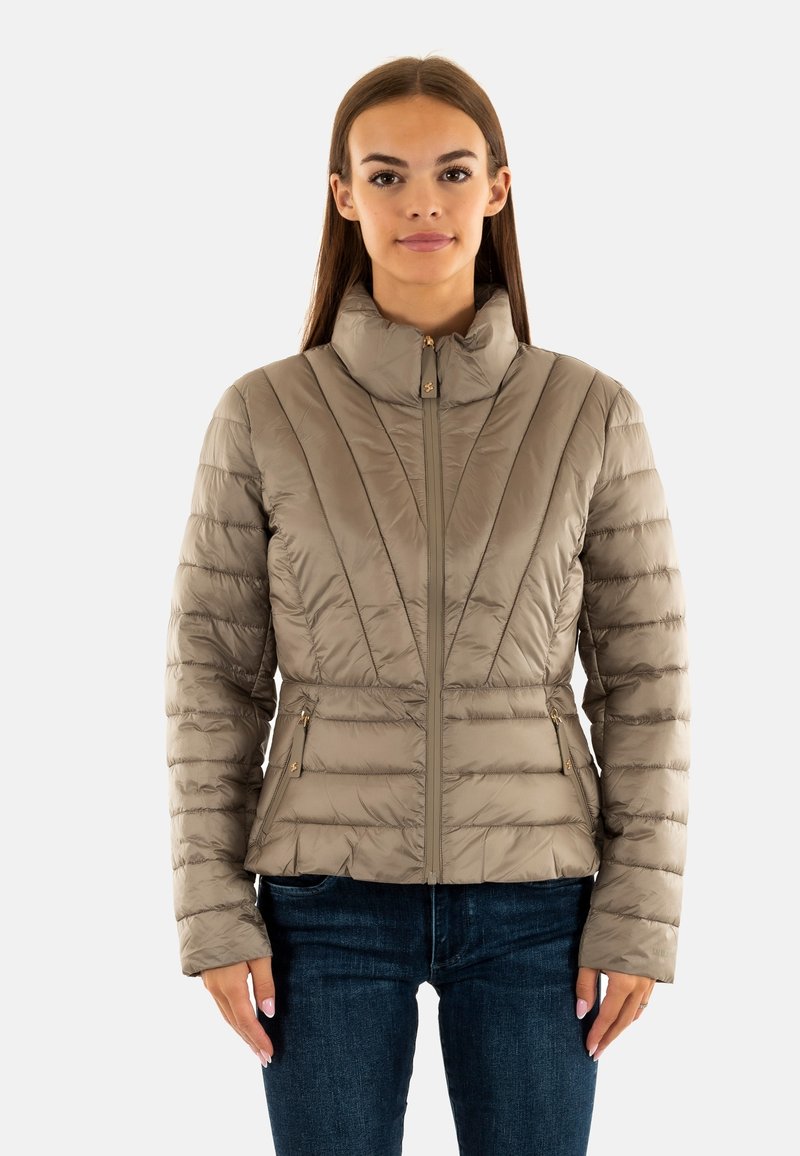 Veste rembourrée de couleur beige clair avec un col haut, fermeture éclair et coutures verticales, dotée de deux poches latérales avec des zips.