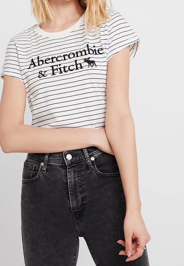 T-shirt a maniche corte a righe bianche e nere con logo "Abercrombie & Fitch", abbinato a jeans neri a vita alta.