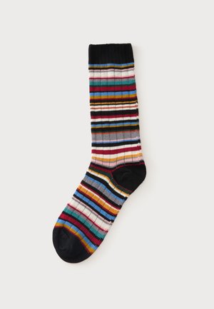 Chaussette rayée colorée unique avec texture côtelée et bord, talon et orteils noirs sur fond clair uni.