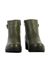 Bottines en cuir vert avec une texture lisse, bouts ronds et un talon épais. Présentent un détail de boucle sur le côté et des semelles en caoutchouc noir.