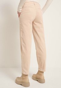 Ljusrosa kordbyxor med rak passform, med bakfickor och en strukturerad yta, ihopparade med ljusbeige ankelstövlar.