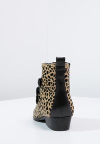 Leopard print ankle boot with black leather accents, featuring a low heel and three decorative straps on the side, made from textured material.