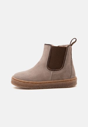 Bottine Chelsea en daim gris avec un panneau latéral élastique marron, semelle en caoutchouc et languette à l'arrière.
