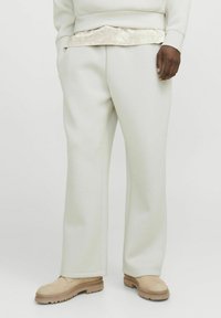 Pantaloni albi, cu croi drept, dintr-o țesătură moale, cu buzunare laterale și un luciu subtil. Asortați cu pantofi bej, texturat.