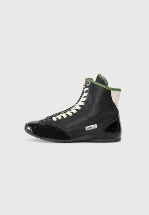 Sneaker alte nere con dettagli verdi, lacci bianchi e suola in gomma nera texturizzata. Presenta una punta lucida e un logo laterale.